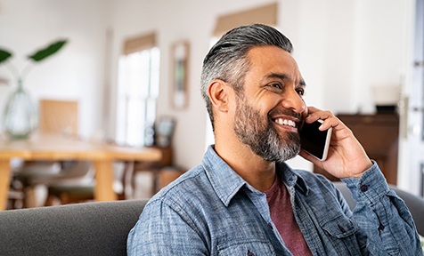 Man in blue shirt smiling while talking on phone