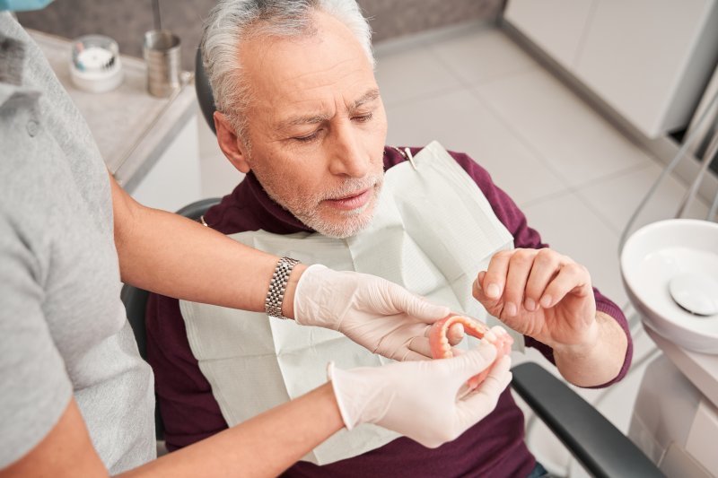 A dentist showing dentures to an older man