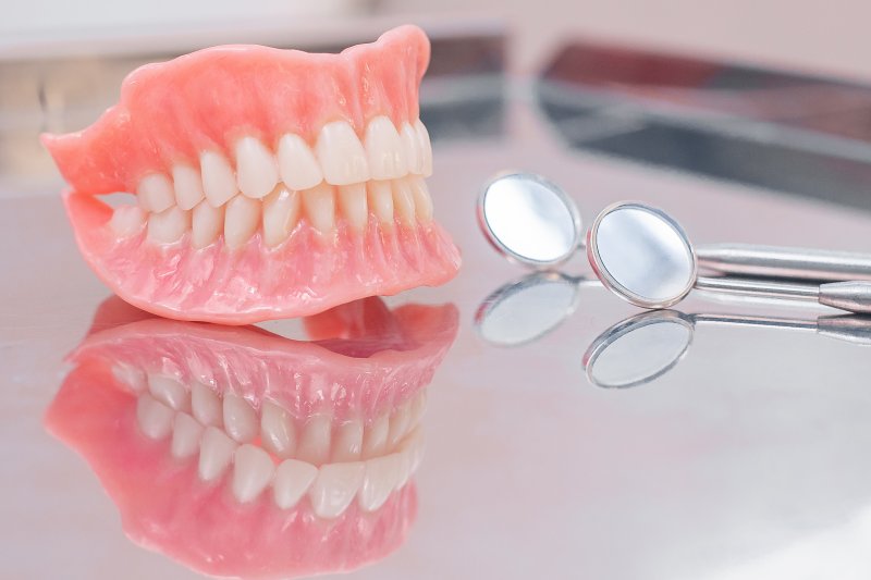 Two full dentures sitting on a reflective surface