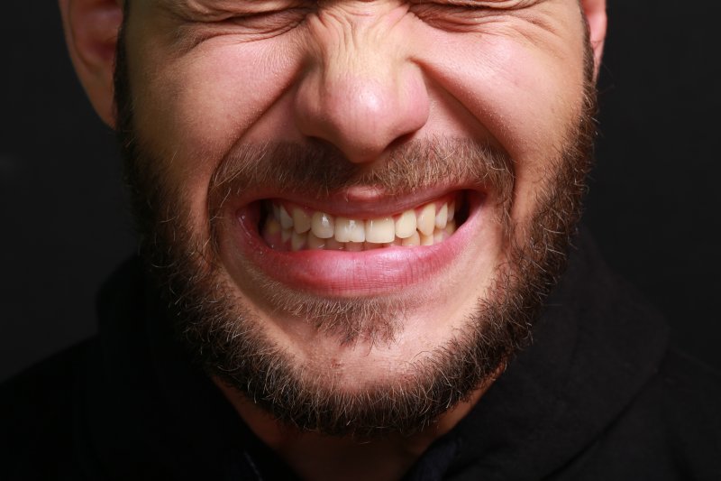 A closeup of a bearded man grinding his teeth